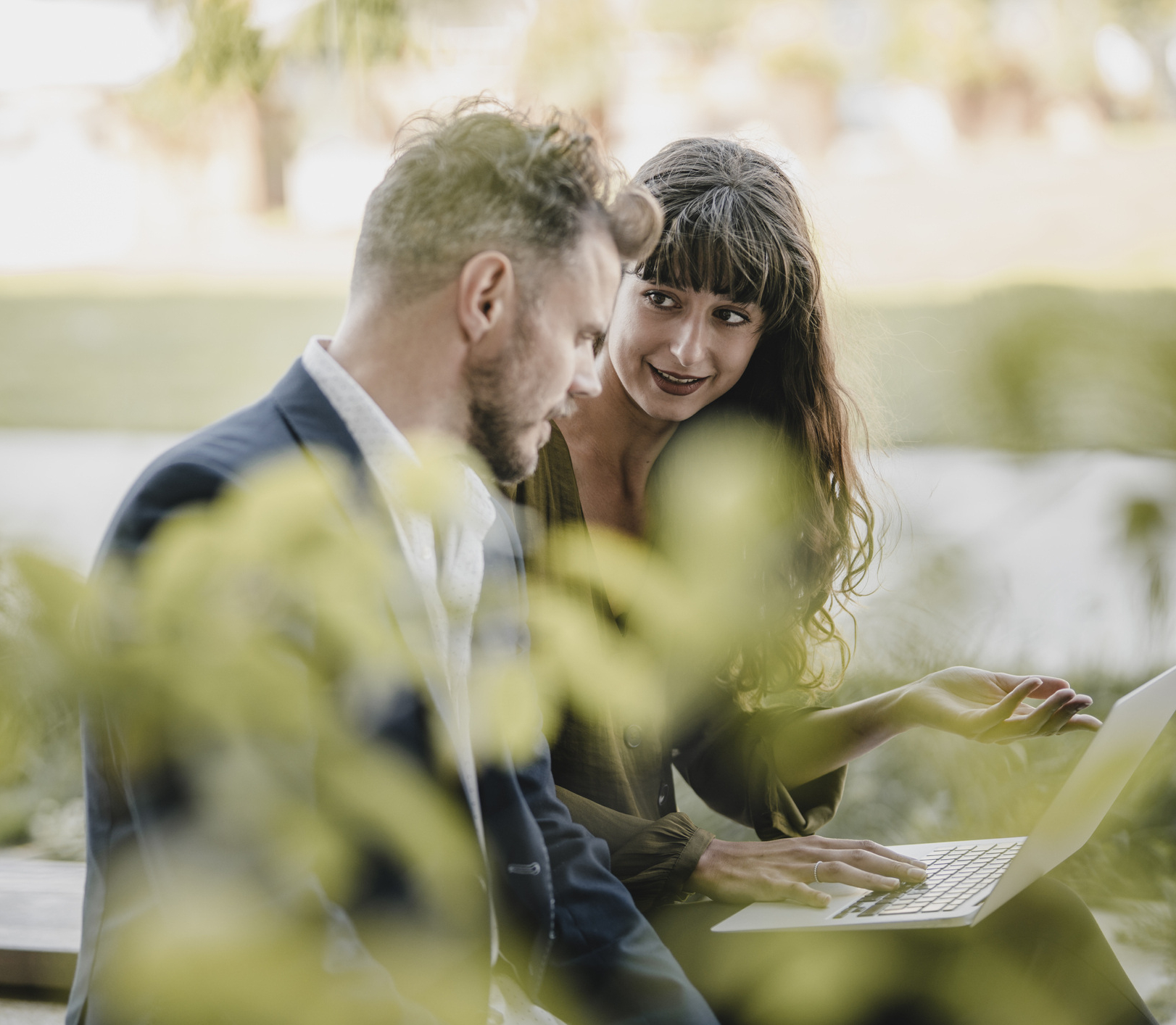 Mann und Frau sitzen im Freien und betrachten ein Laptop, um Energiemanagementlösungen zu diskutieren.